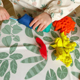 Children's hands playing with colourful Play-Doh on a leaf-patterned splash mat