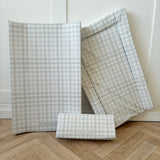 Sage green changing mat bundle with three changing mats on a wooden floor with a white wall background