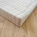 Wedge baby changing mat with checkered pattern on a wooden floor