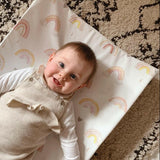 baby smiling on top of a rainbow print changing mat