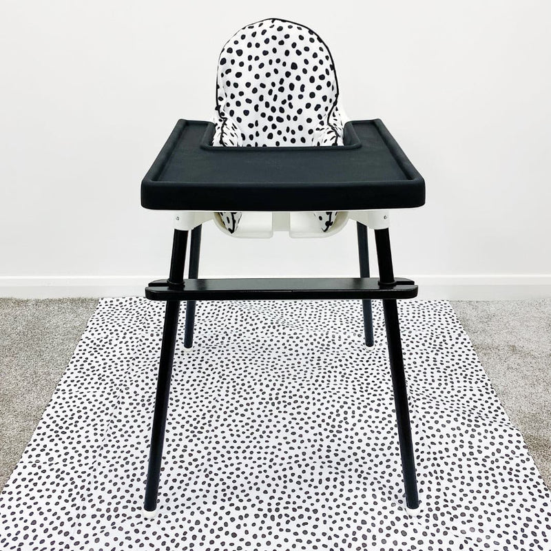 IKEA highchair with spotty cushion cover, black legs, black footrest and black tray on top of a spotty splash mat