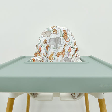 IKEA highchair with jungle animals cover and sage green tray wrap against white wall